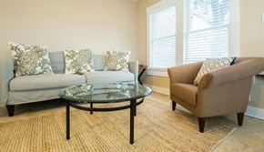 Fort Worth house for rent - A living room with a grey couch, a glass coffee table, and a brown armchair.