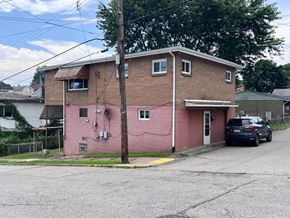 Glassport apartment for rent - A pink building with a car parked in front.