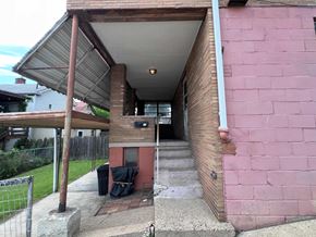 Glassport apartment for rent - A pink building with a covered walkway leading to the front door.