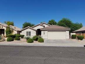 Chandler house for rent - A house with a brown roof and a garage door is surrounded by bushes and trees.