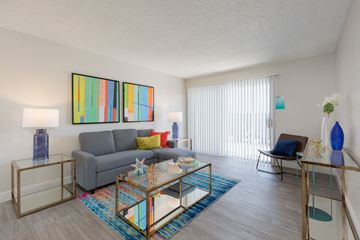 Phoenix apartment for rent - A living room with a grey couch, a glass coffee table, and a painting on the wall.