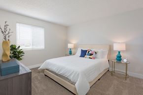 Phoenix apartment for rent - A bedroom with a white bed and a blue lamp on a side table.