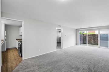 Columbus apartment for rent - A spacious living room with a grey carpet and a view of a fenced area outside the window.