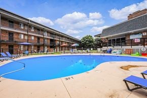 Columbus apartment for rent - A large blue swimming pool in front of a building with a poolside bar.