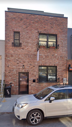 Brooklyn apartment for rent - A silver car is parked in front of a red brick building.