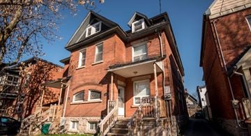 Ottawa apartment for rent - A red brick house with a black car parked in front.