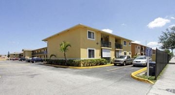 Hialeah apartment for rent - a yellow apartment building with cars parked in a parking lot