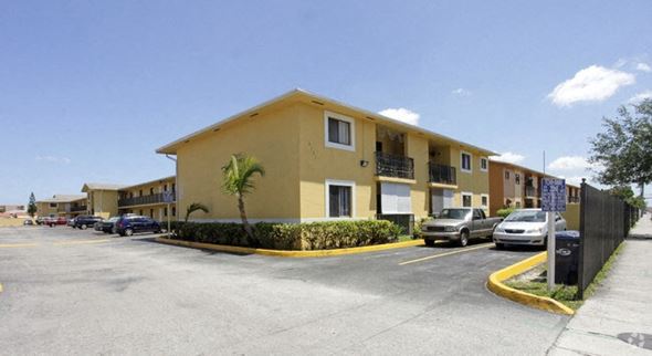 Hialeah apartment for rent - a yellow apartment building with cars parked in a parking lot