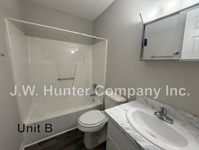 Wilson apartment for rent - A bathroom with a toilet, sink, and mirror.