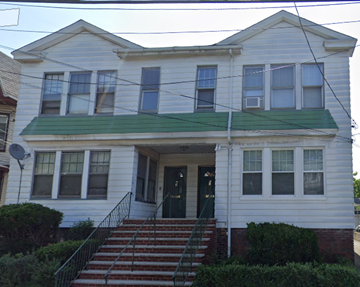 Irvington apartment for rent - A white house with a green roof and a black staircase.