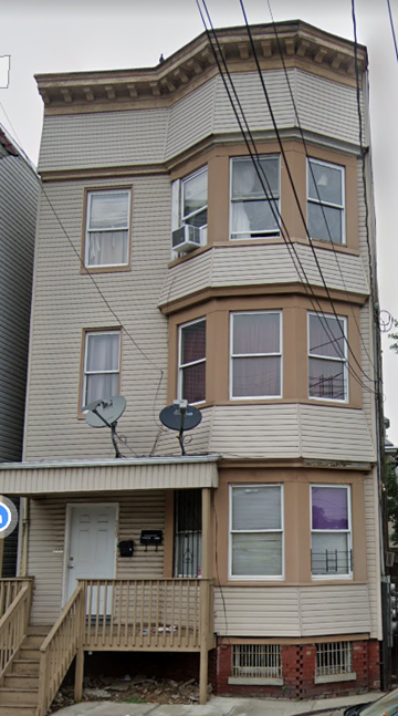 Irvington apartment for rent - A three-story building with a balcony and satellite dishes on the roof.