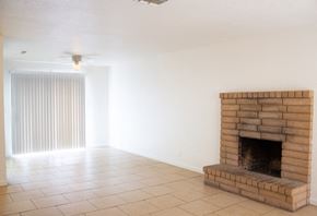 Merced house for rent - an empty living room with a brick fireplace and a ceiling fan