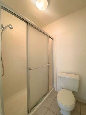 Merced house for rent - A white toilet sits next to a glass shower door in a bathroom.