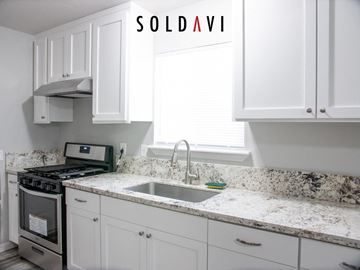Merced house for rent - A kitchen with white cabinets and a granite countertop.
