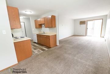 Grand Forks apartment for rent - a kitchen and living room with a carpeted floor and wooden cabinets