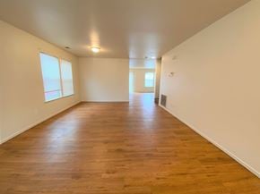 Merced house for rent - the living room and dining room of an empty house with wood floors