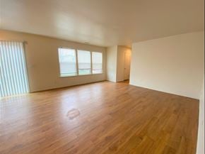 Merced house for rent - the living room and dining room of an empty house with wood floors
