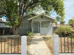 Merced house for rent - A house with a grey front yard and a black fence.