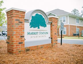 Thomasville apartment for rent - a sign for market station apartments in front of a brick building
