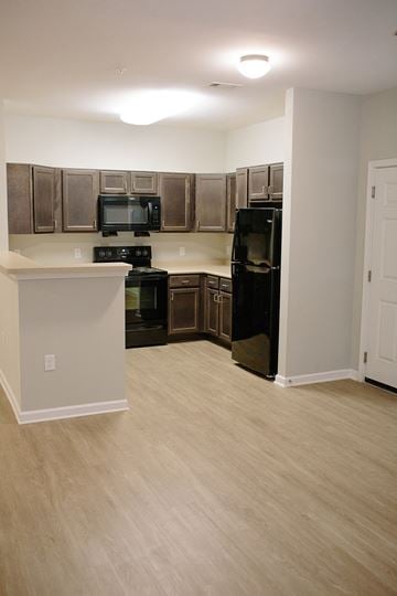 Valdosta apartment for rent - an empty kitchen with black appliances and wood flooring