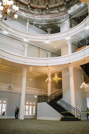 Pelham apartment for rent - a man standing in the lobby of a large building with a spiral staircase