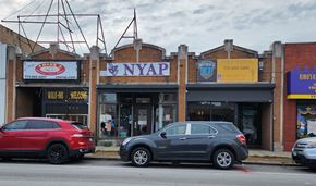 Chicago apartment for rent - Two cars are parked in front of a building with a sign that reads "NYAP.".