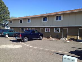 Kennewick apartment for rent - A blue pickup truck is parked in a parking lot in front of a building.