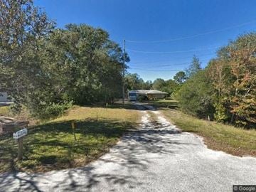 Clearwater apartment for rent - A gravel road leads to a house surrounded by trees.