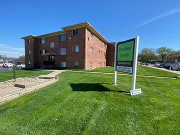 Omaha apartment for rent - A sign for Dundee Creek Apartments stands in front of a brick building.