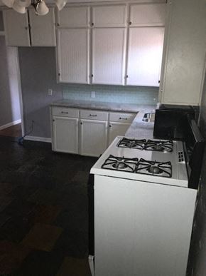 Snyder house for rent - an empty kitchen with a stove and white cabinets