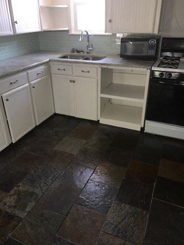Snyder house for rent - a kitchen with white cabinets and a sink