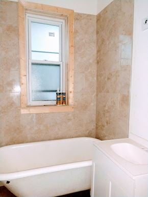 Chicago apartment for rent - A bathroom with a tub, sink and window.