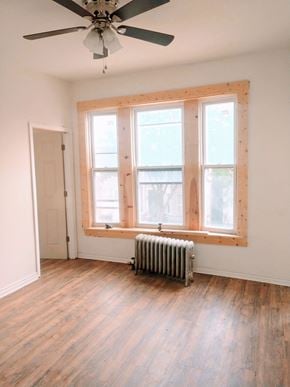 Chicago apartment for rent - A room with a ceiling fan and a window with a radiator under it.