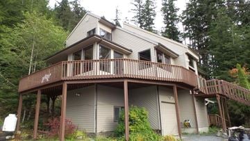 Stika apartment for rent - A house with a balcony and a deck in the woods.