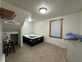 Sitka house for rent - A bedroom with a bed, a chair, and a window.