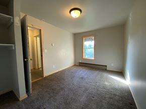 Sitka house for rent - A room with a carpeted floor, a window with a view of trees, and a small light fixture on the ceiling.