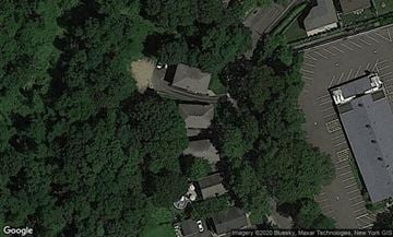 Port Washington apartment for rent - A satellite image shows a parking lot and a building surrounded by trees.