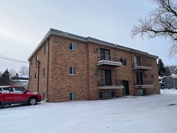 Moorhead apartment for rent - A red car is parked in front of a brick building.