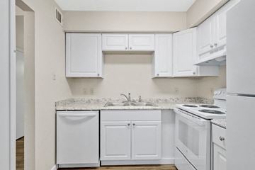 Slidell apartment for rent - a kitchen with white appliances and white cabinets