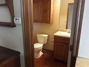 Stillwater house for rent - A bathroom with a toilet, sink, and wooden cabinet.