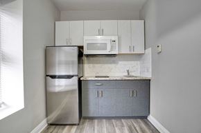 Oshawa apartment for rent - a small kitchen with white cabinets and a stainless steel refrigerator