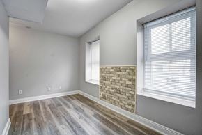 Oshawa apartment for rent - an empty living room with a stone fireplace and wood floors
