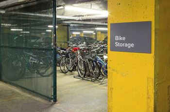 Bike storage area with bikes parked behind a fence.