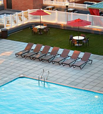 A pool with a few chairs and umbrellas.