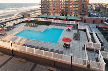 A large pool with a table and chairs is surrounded by a white fence.