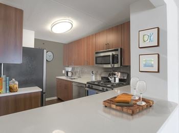 A kitchen with a white counter top and wooden cabinets.