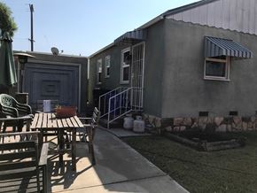 San Diego house for rent - an exterior view of a small gray house with a table and chairs