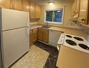 Sitka apartment for rent - a kitchen with white appliances and wooden cabinets