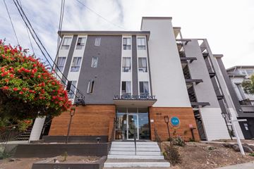 Oakland apartment for rent - A modern building with a red flower bush in front.