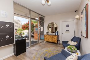 Oakland apartment for rent - A living room with a blue couch and a mirror on the wall.